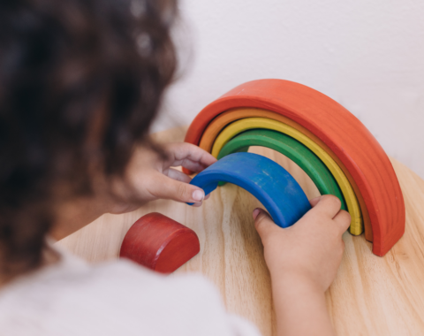 Child playing with wooden rainbow toy